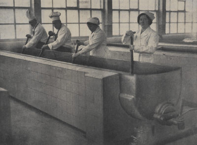 300253 Afbeelding van enkele koks bij de kookketels in het nieuwe gebouw van de Centrale Keuken (gaarkeuken, ...